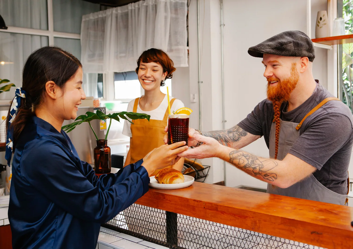 Une cliente souriante échange avec les commerçants d'un café